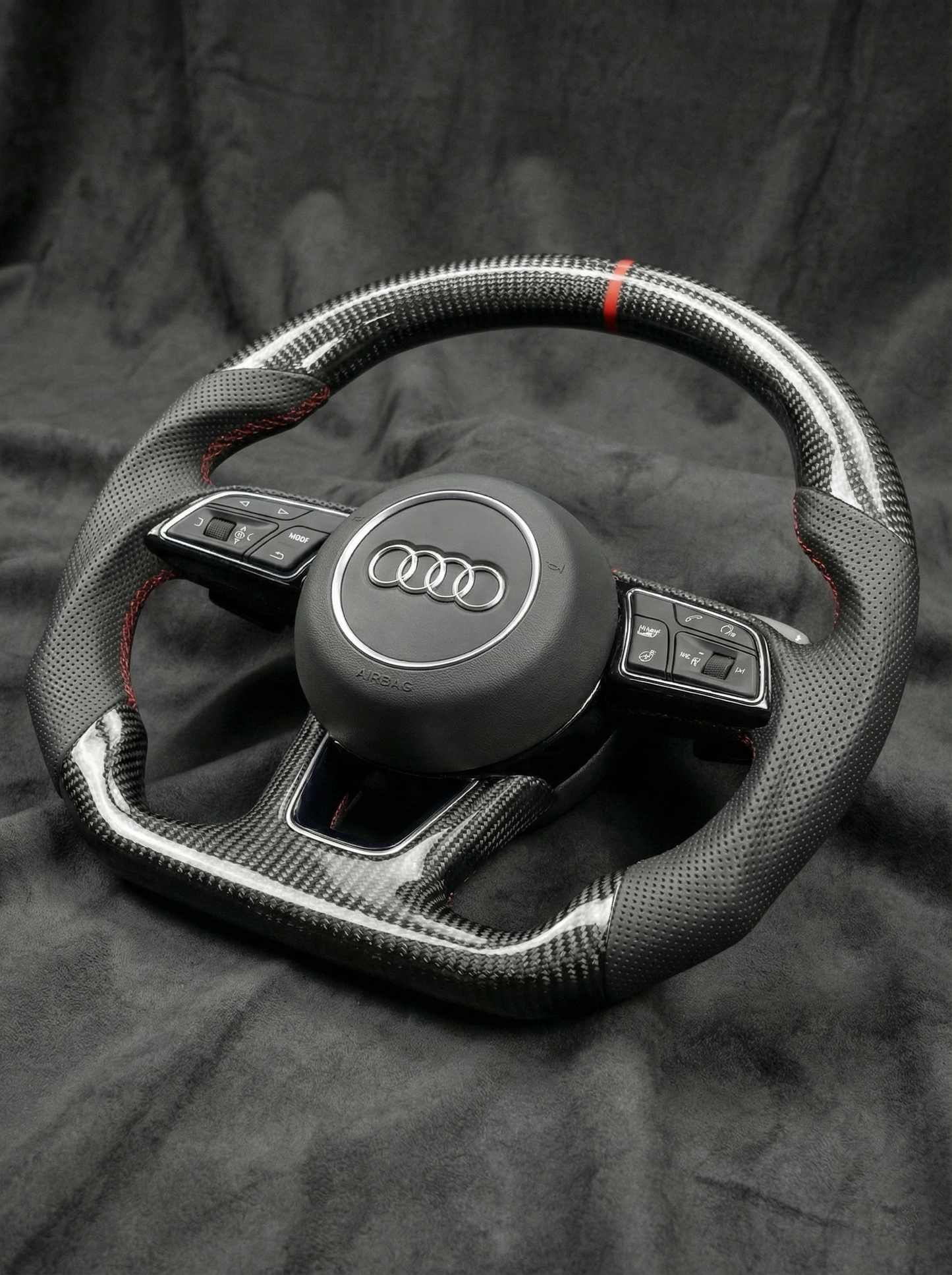 Carbon fiber steering wheel with Audi logo on a dark background