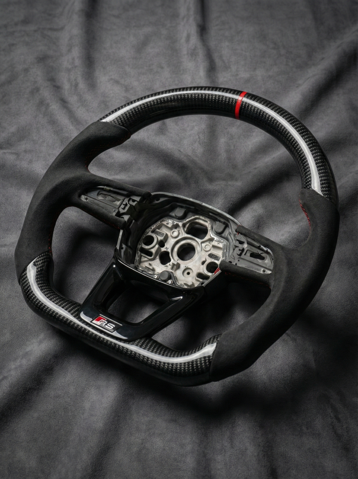 Carbon fiber steering wheel with silver center on a dark fabric background