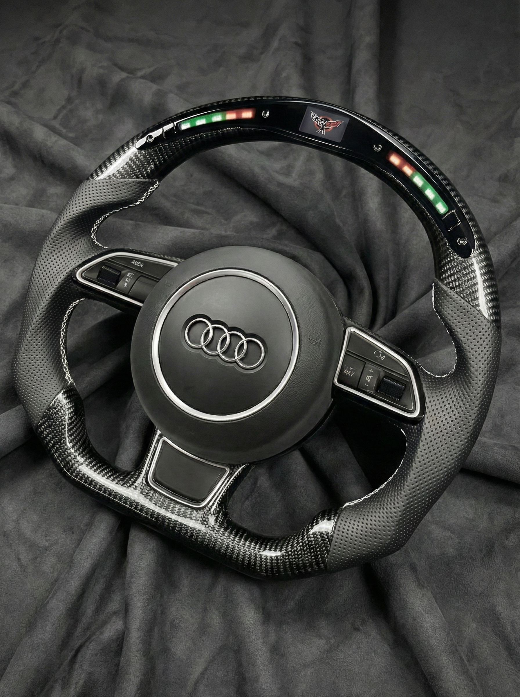 Carbon fiber steering wheel with Audi logo on a dark background