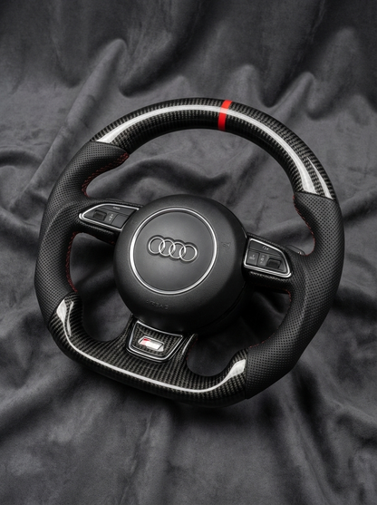 Carbon fiber steering wheel with Audi logo on a dark fabric background