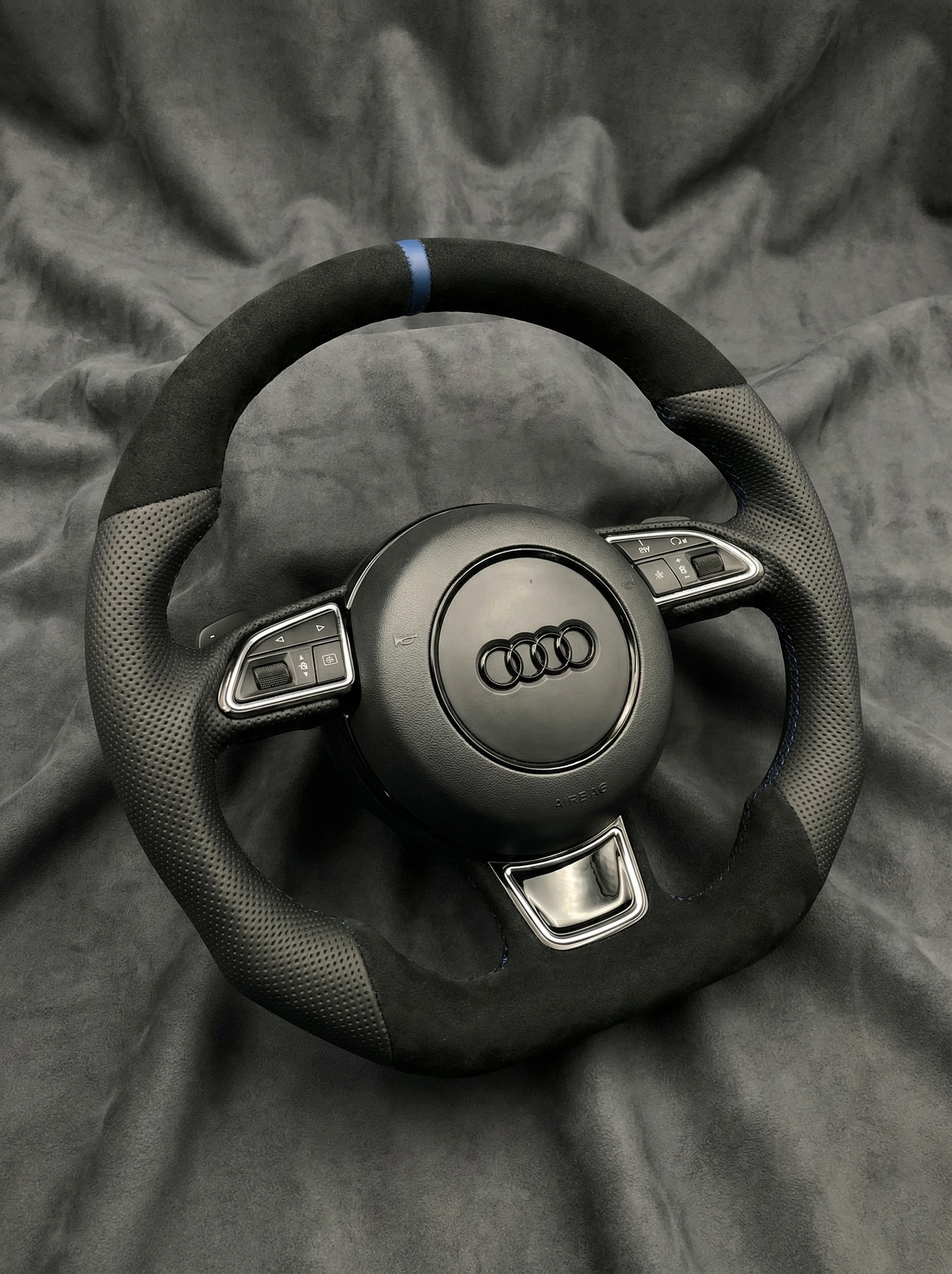 Steering wheel with Audi logo on a gray fabric background