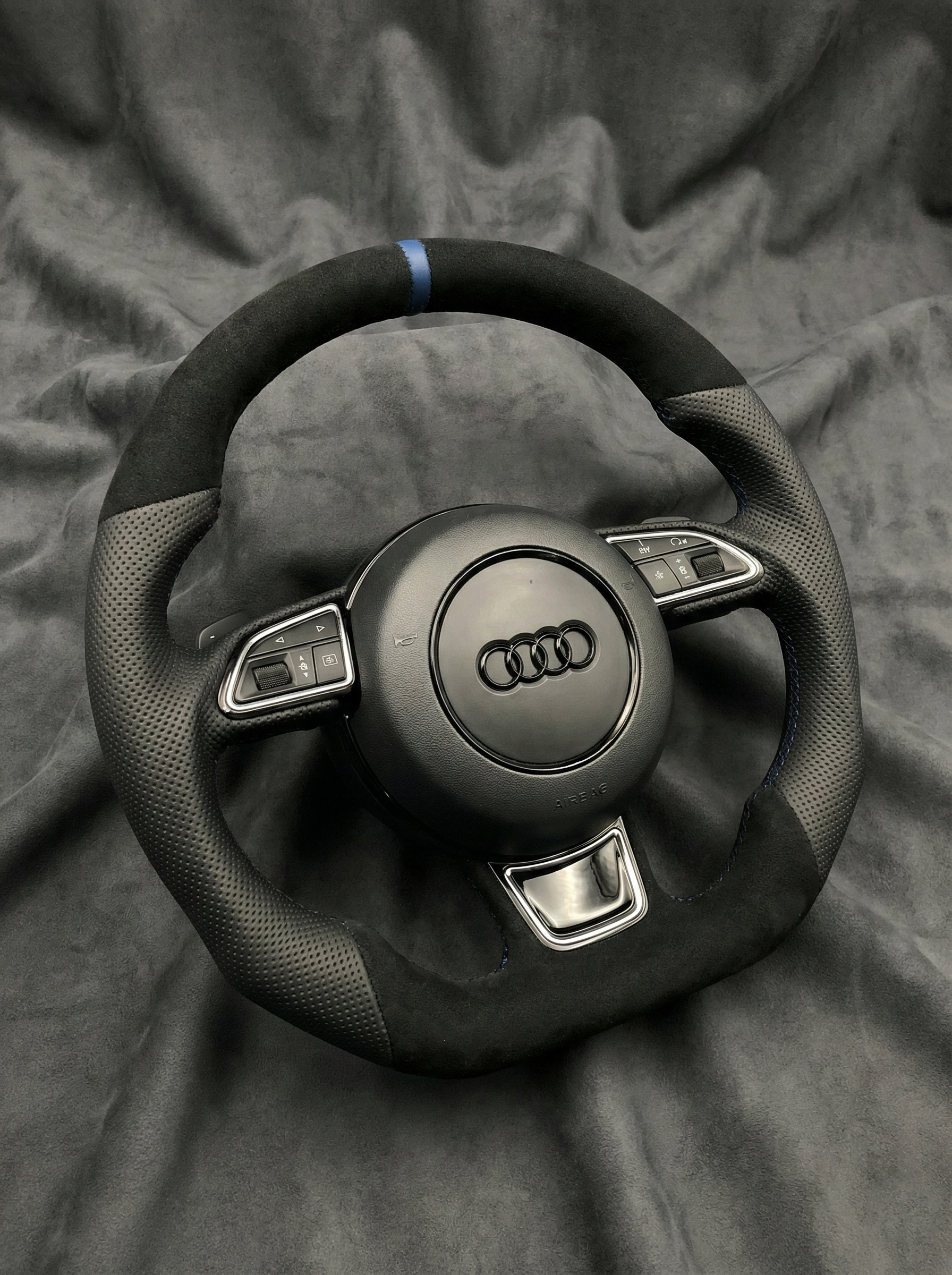 Steering wheel with Audi logo on a gray fabric background