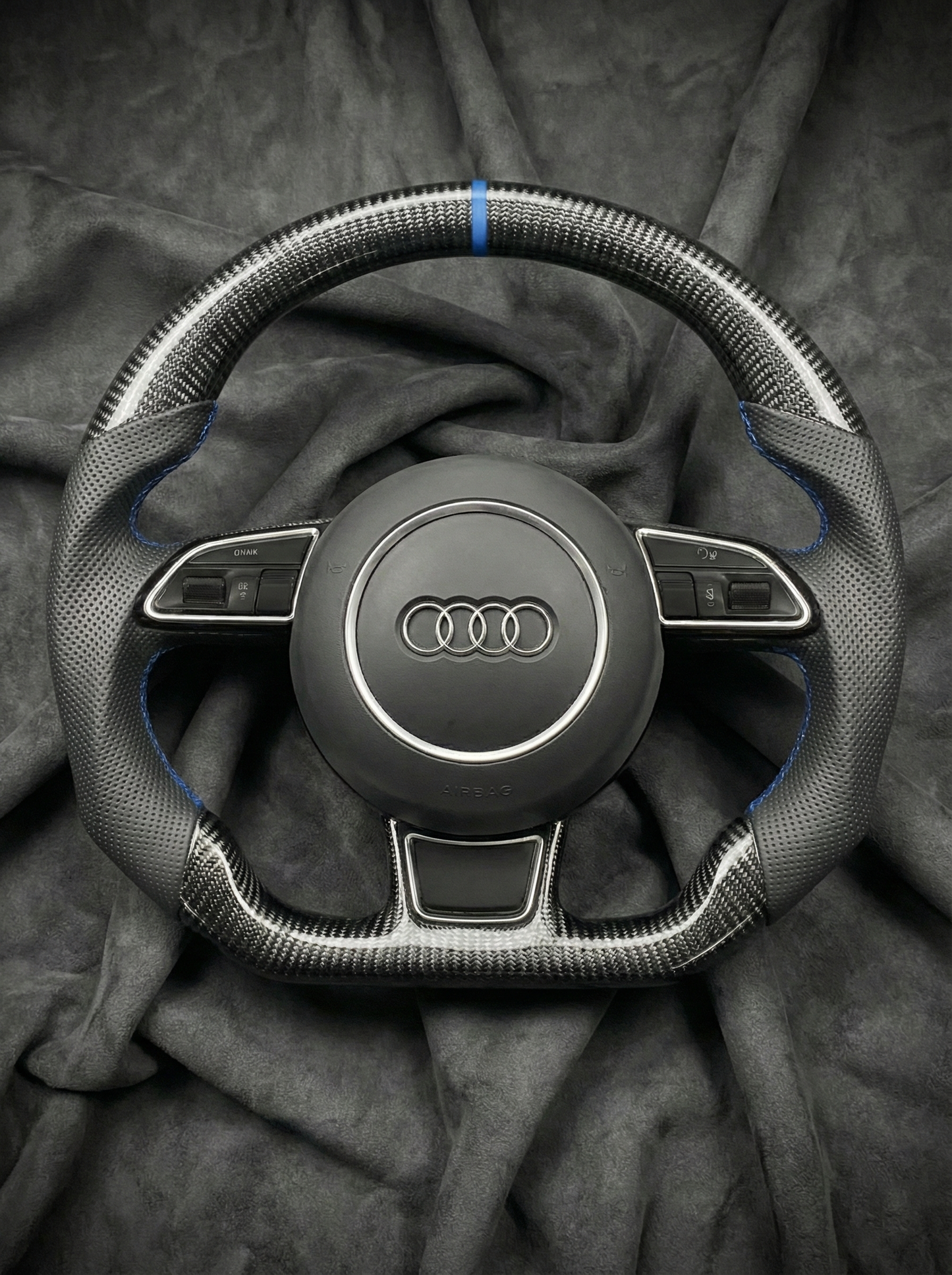 Steering wheel with Audi logo on a dark fabric background