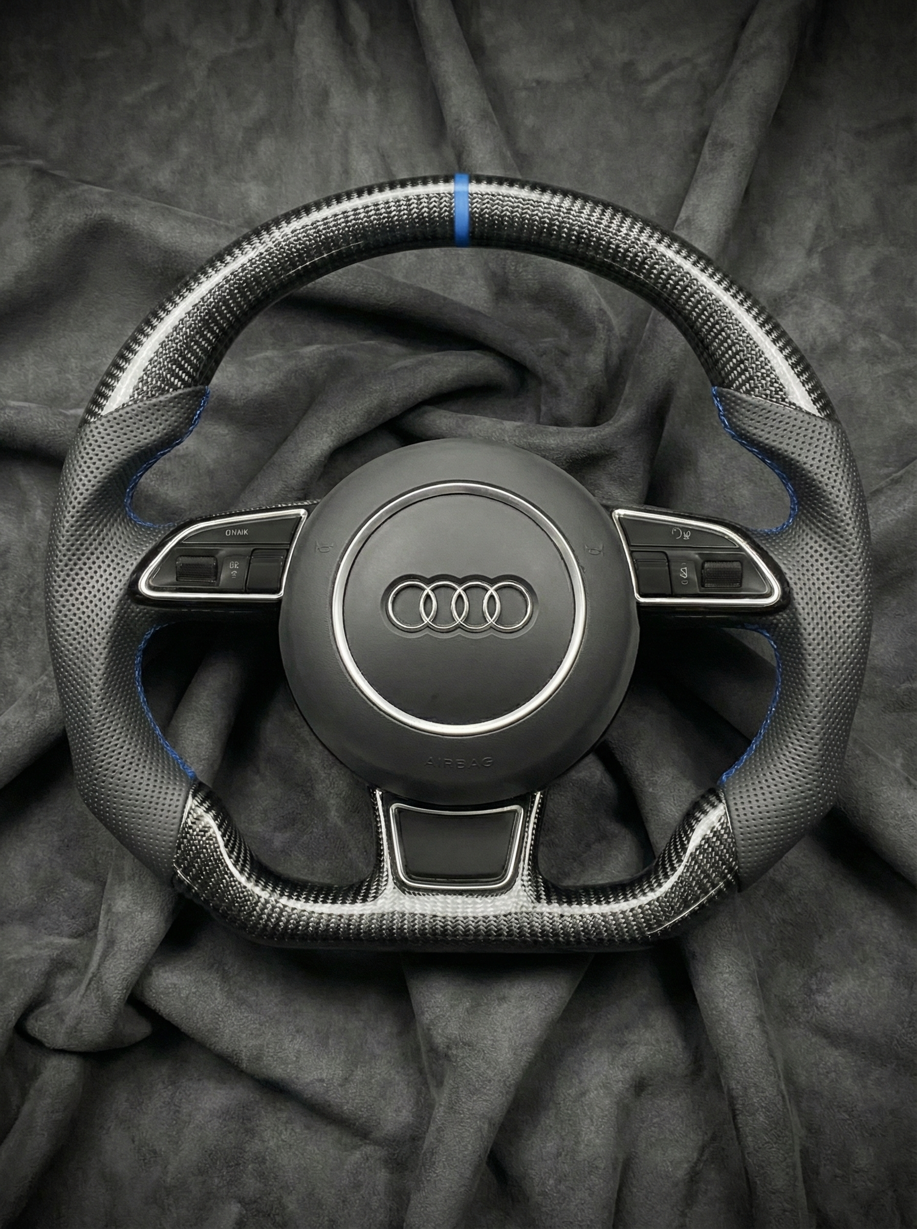 Steering wheel with Audi logo on a dark fabric background