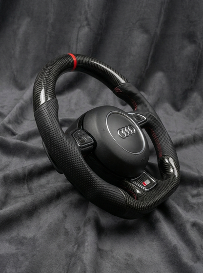 Black Audi steering wheel on a dark fabric background