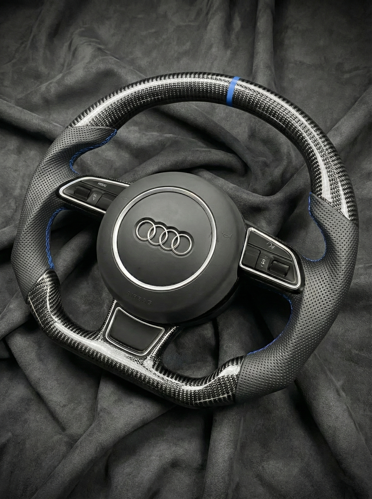 Steering wheel with Audi logo on a dark fabric background