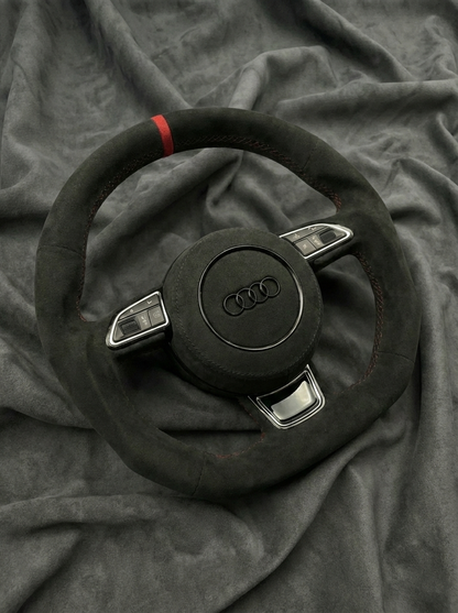 Steering wheel with Audi logo on a gray fabric background
