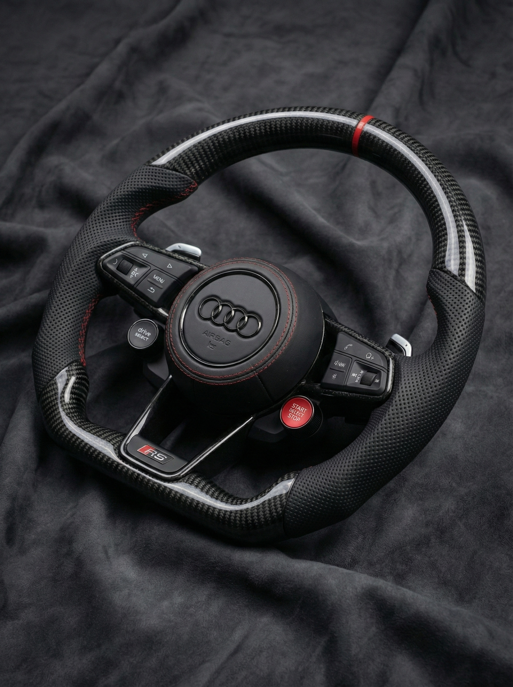 Black Audi steering wheel on a dark fabric background