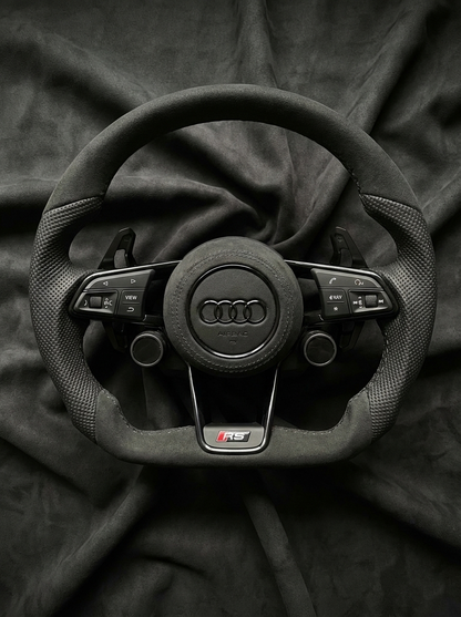 Steering wheel with Audi logo on a black fabric background