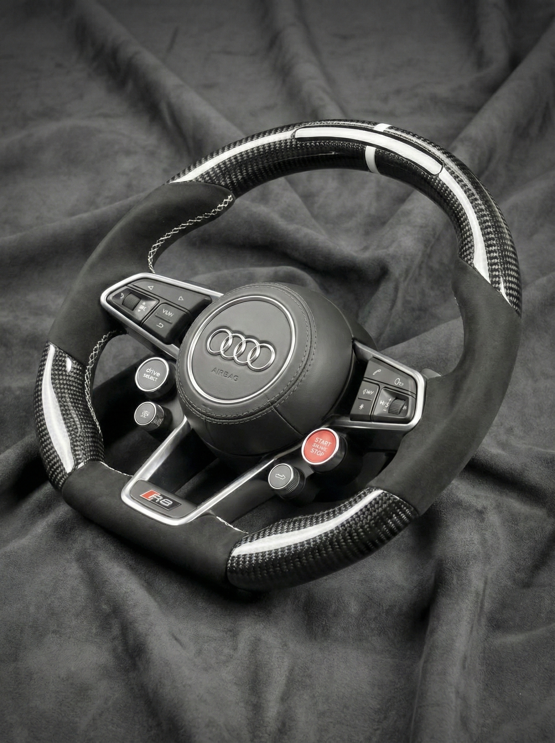 Steering wheel with Audi logo on a dark fabric background