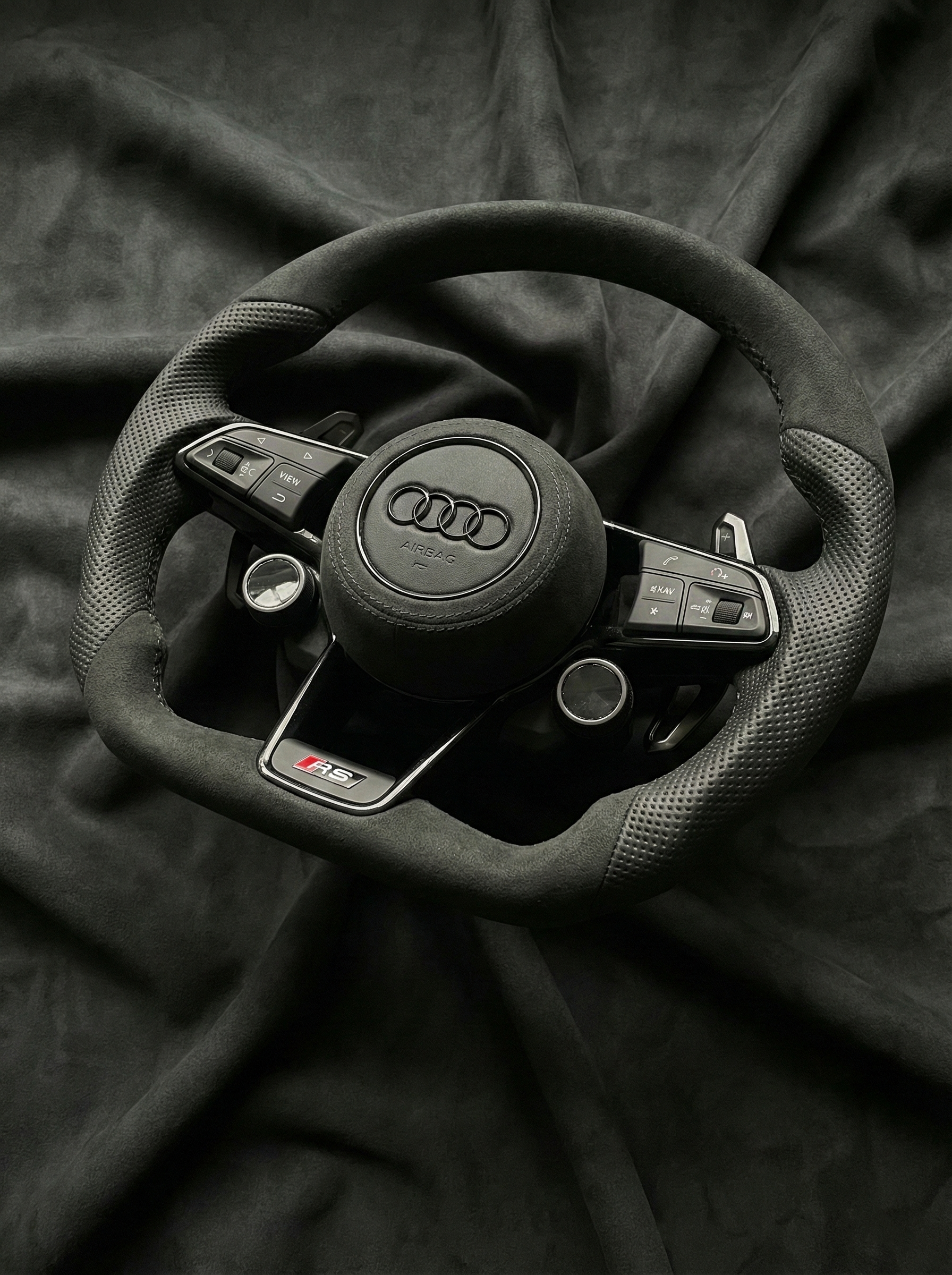 Steering wheel with Audi logo on a dark fabric background