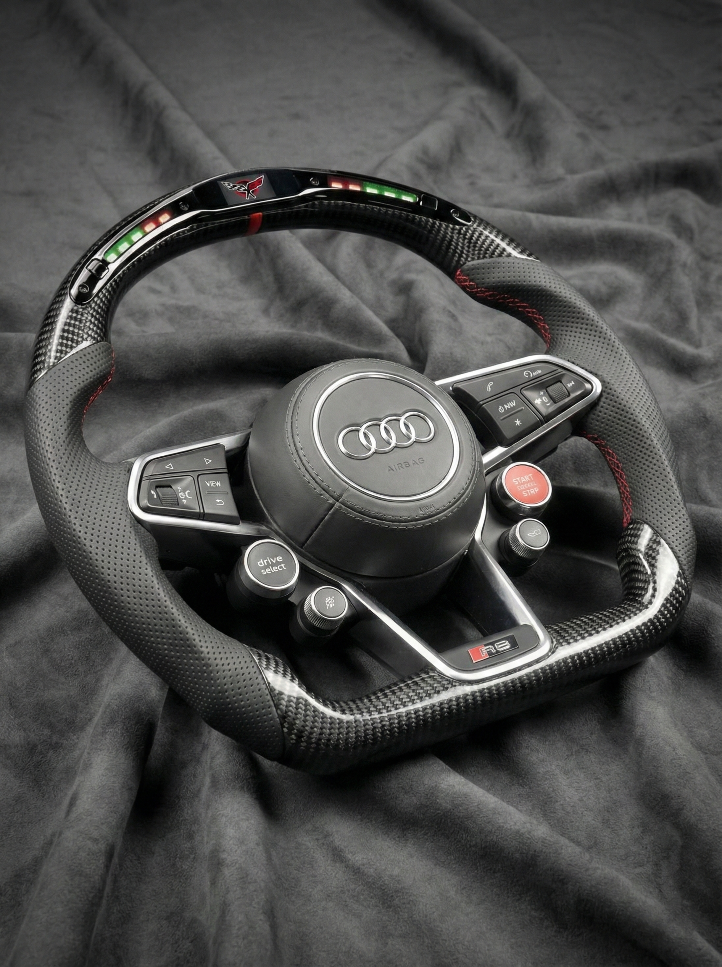Carbon fiber steering wheel with Audi logo on a dark fabric background