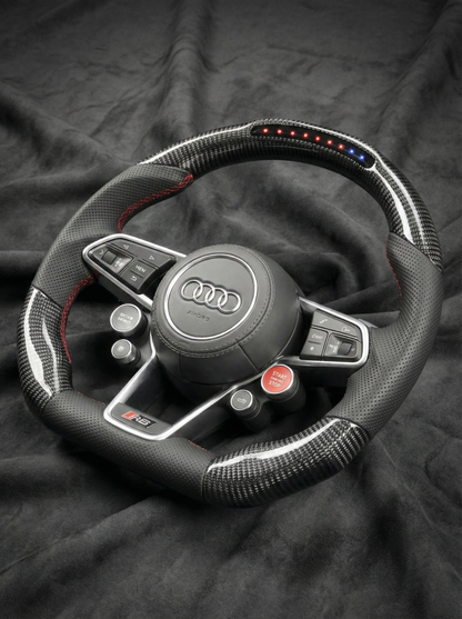 Steering wheel with Audi logo on a dark fabric background