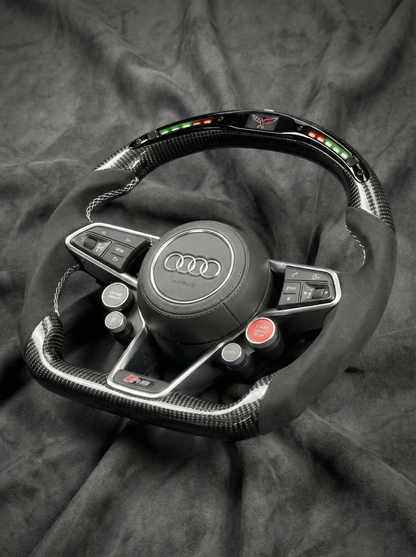 Steering wheel with Audi logo on a dark fabric background