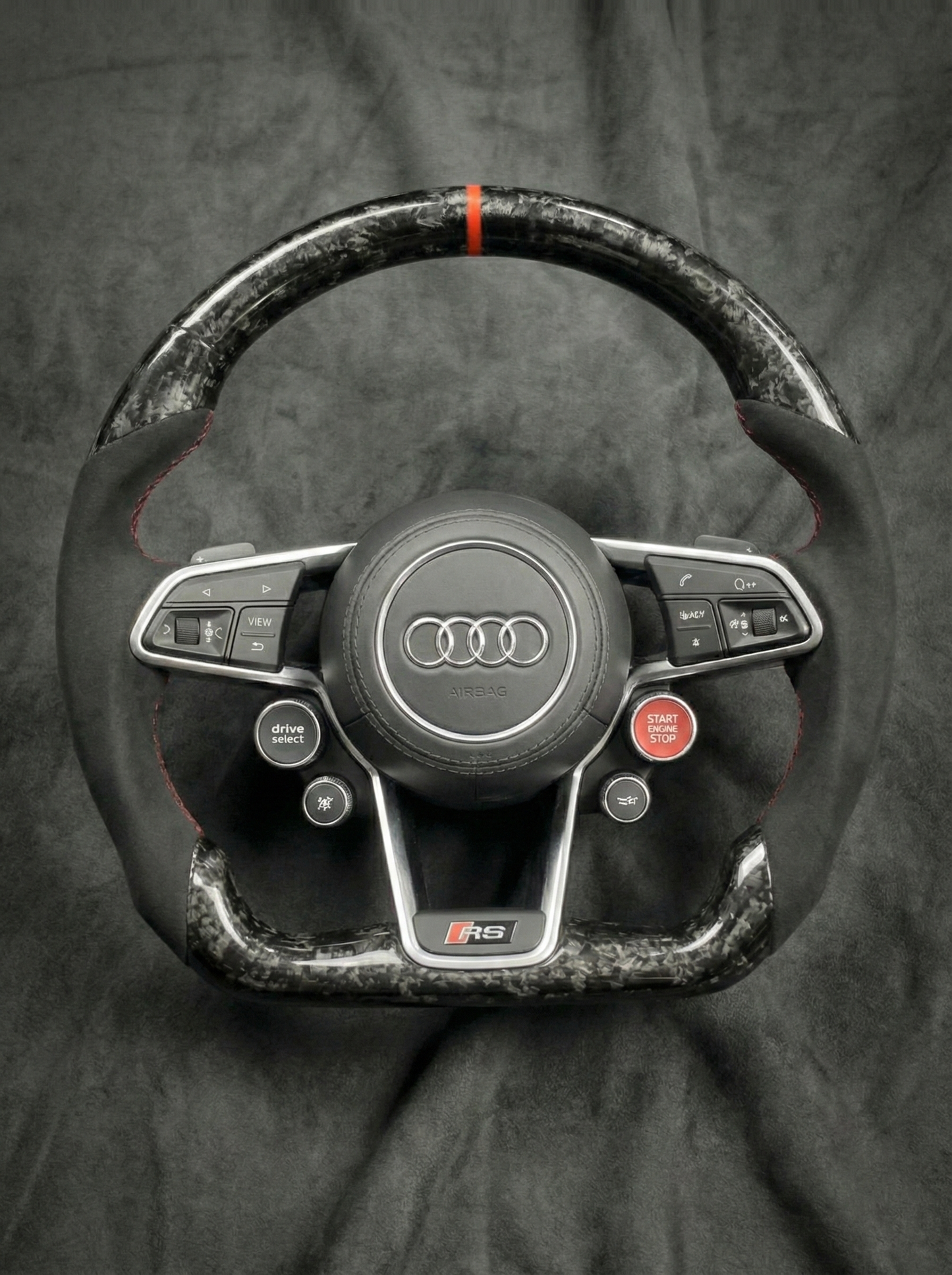 Carbon fiber steering wheel with Audi logo on a dark background