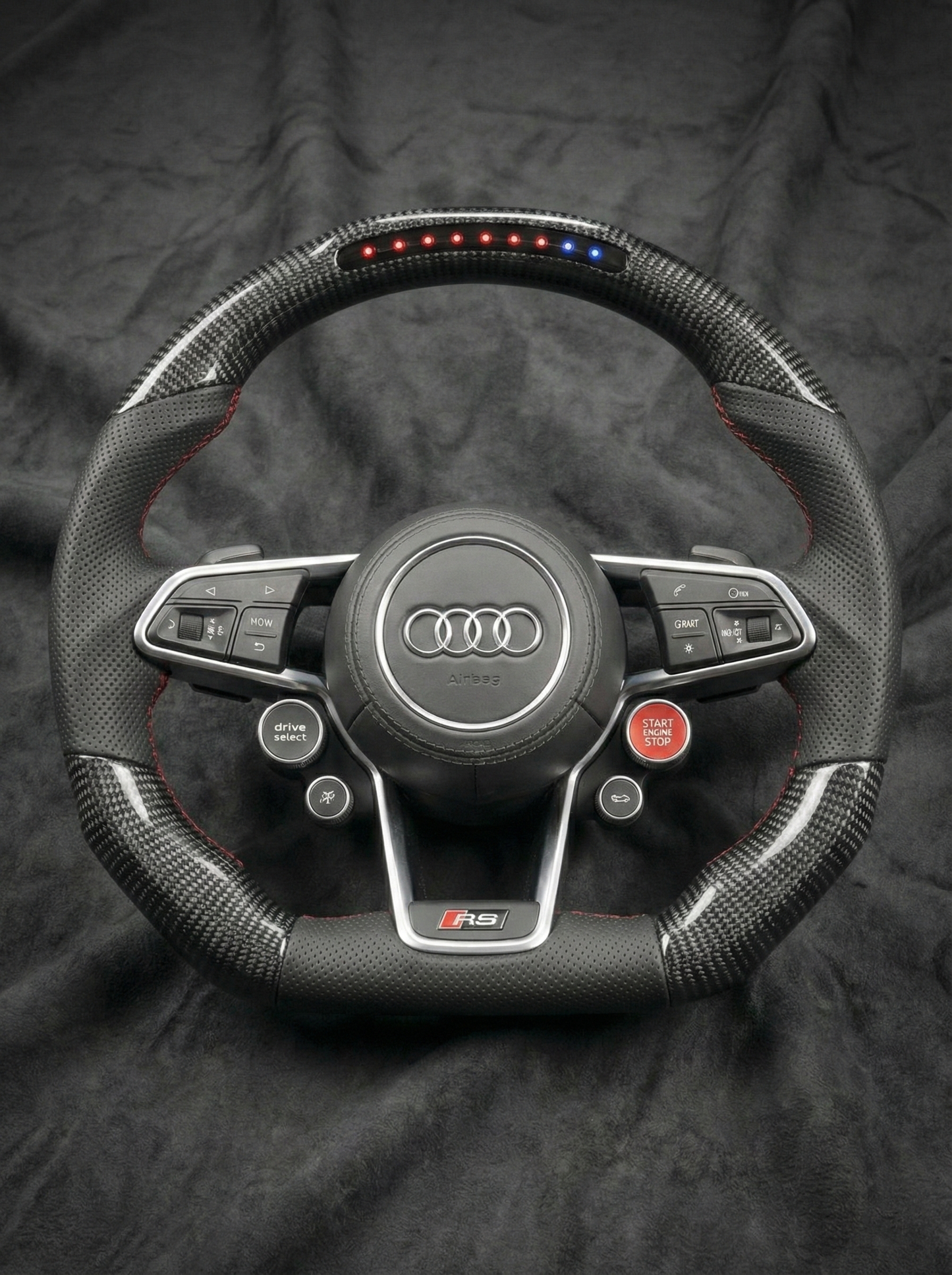 Carbon fiber steering wheel with Audi logo on a dark background