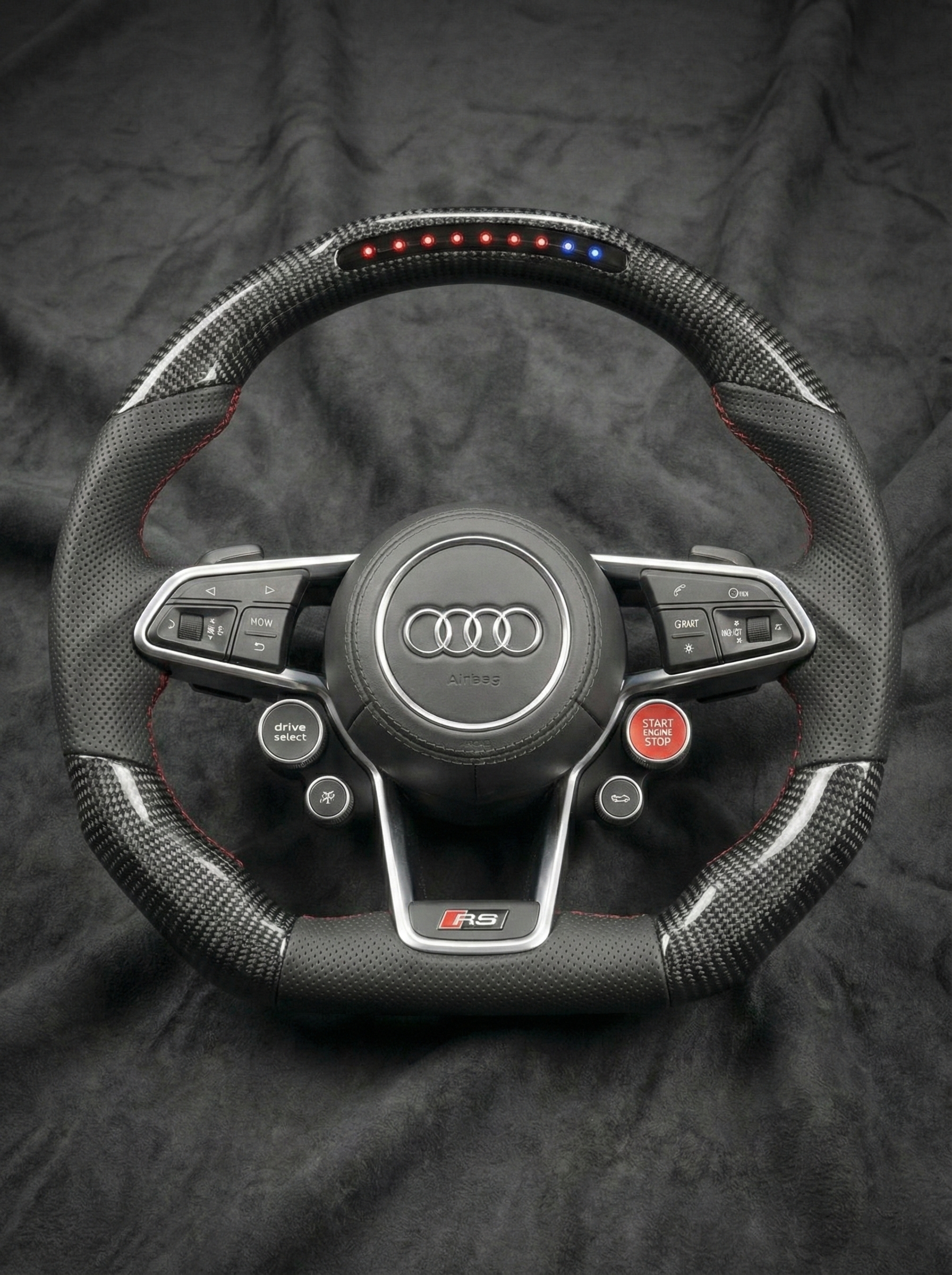 Carbon fiber steering wheel with Audi logo on a dark background