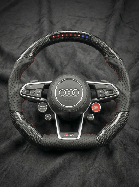 Carbon fiber steering wheel with Audi logo on a dark background