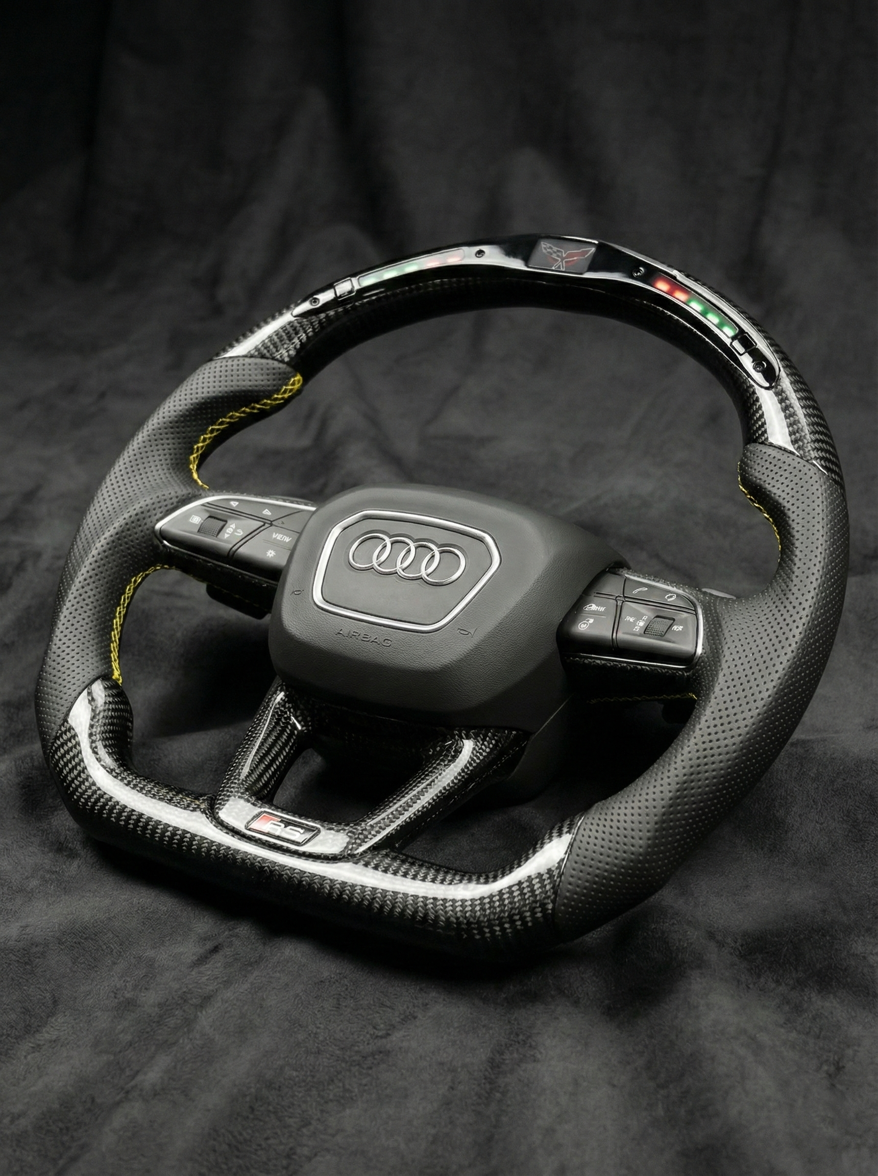 Carbon fiber steering wheel with Audi logo on a dark background