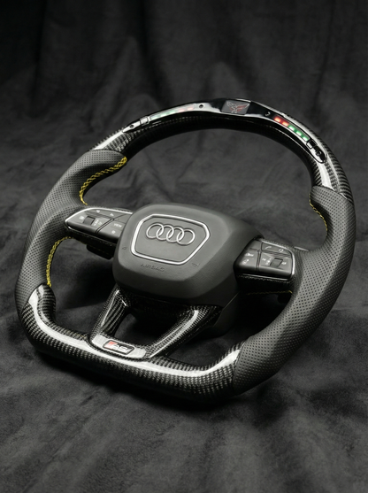 Carbon fiber steering wheel with Audi logo on a dark background
