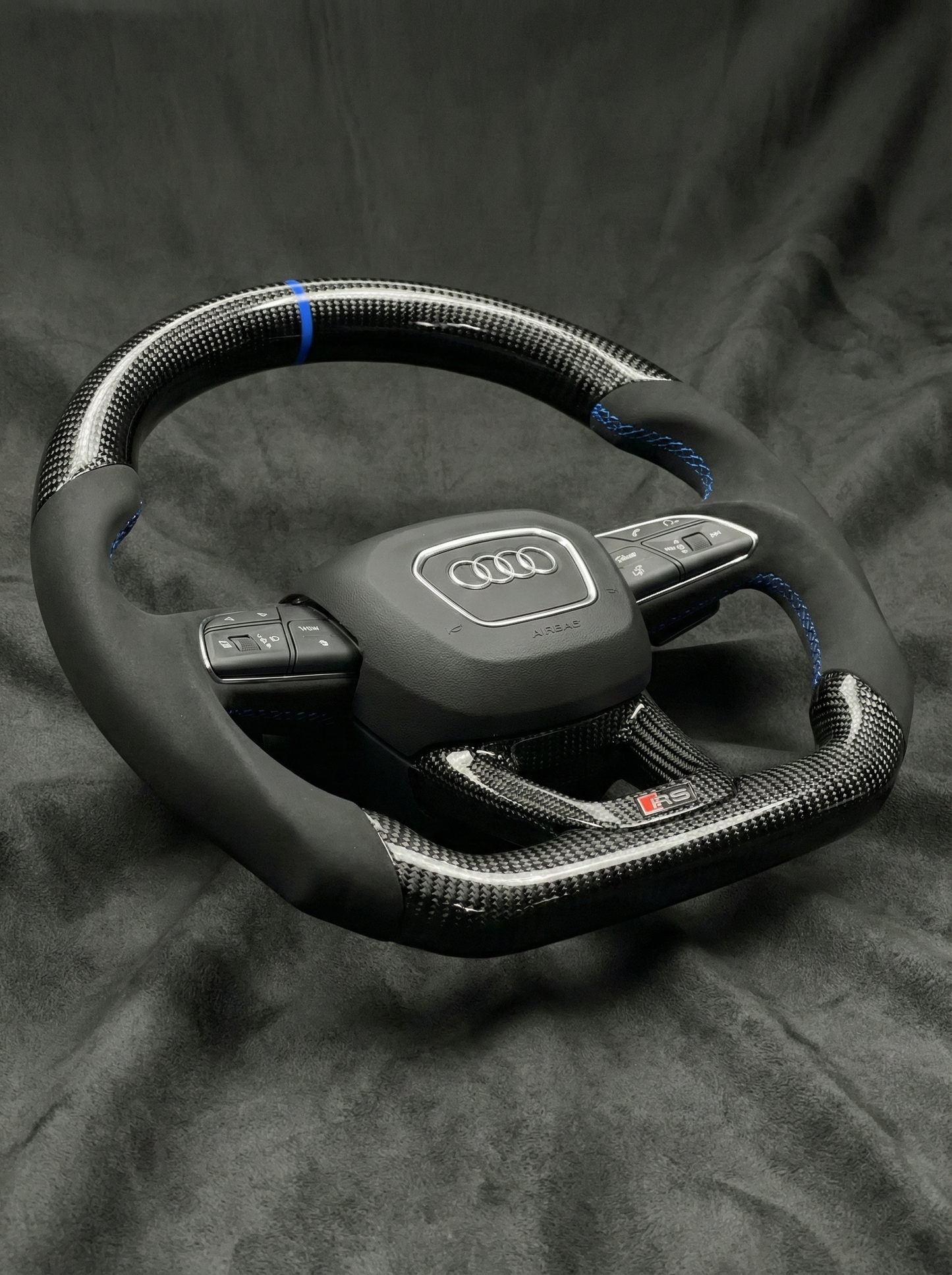 Carbon fiber steering wheel with Audi logo on a dark background