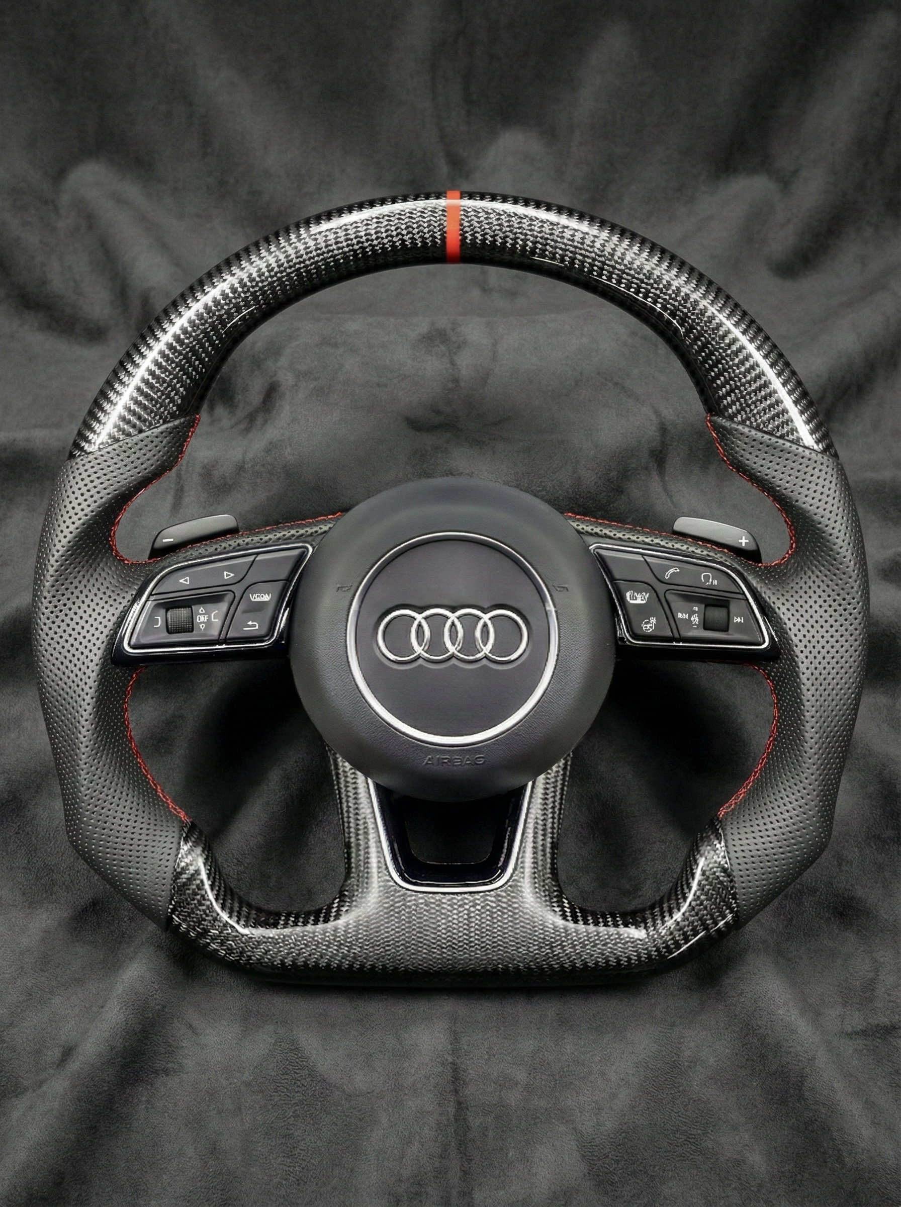 Carbon fiber steering wheel with Audi logo on a dark background