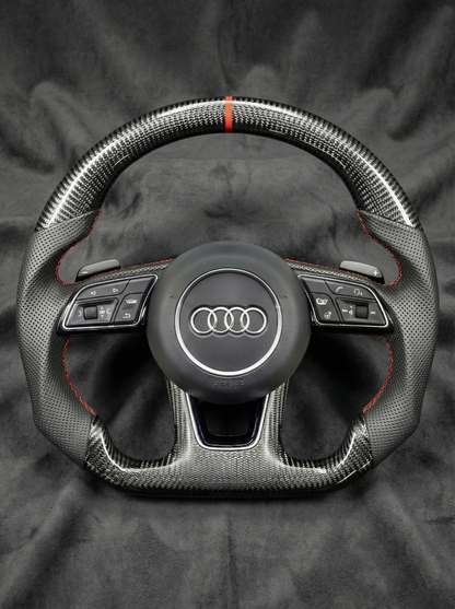 Carbon fiber steering wheel with Audi logo on a dark background
