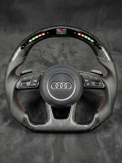 Carbon fiber steering wheel with Audi logo on a dark background