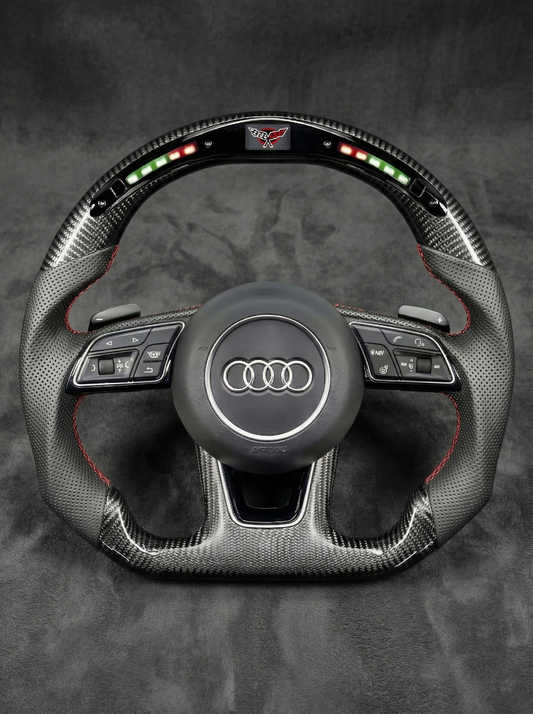 Carbon fiber steering wheel with Audi logo on a dark background