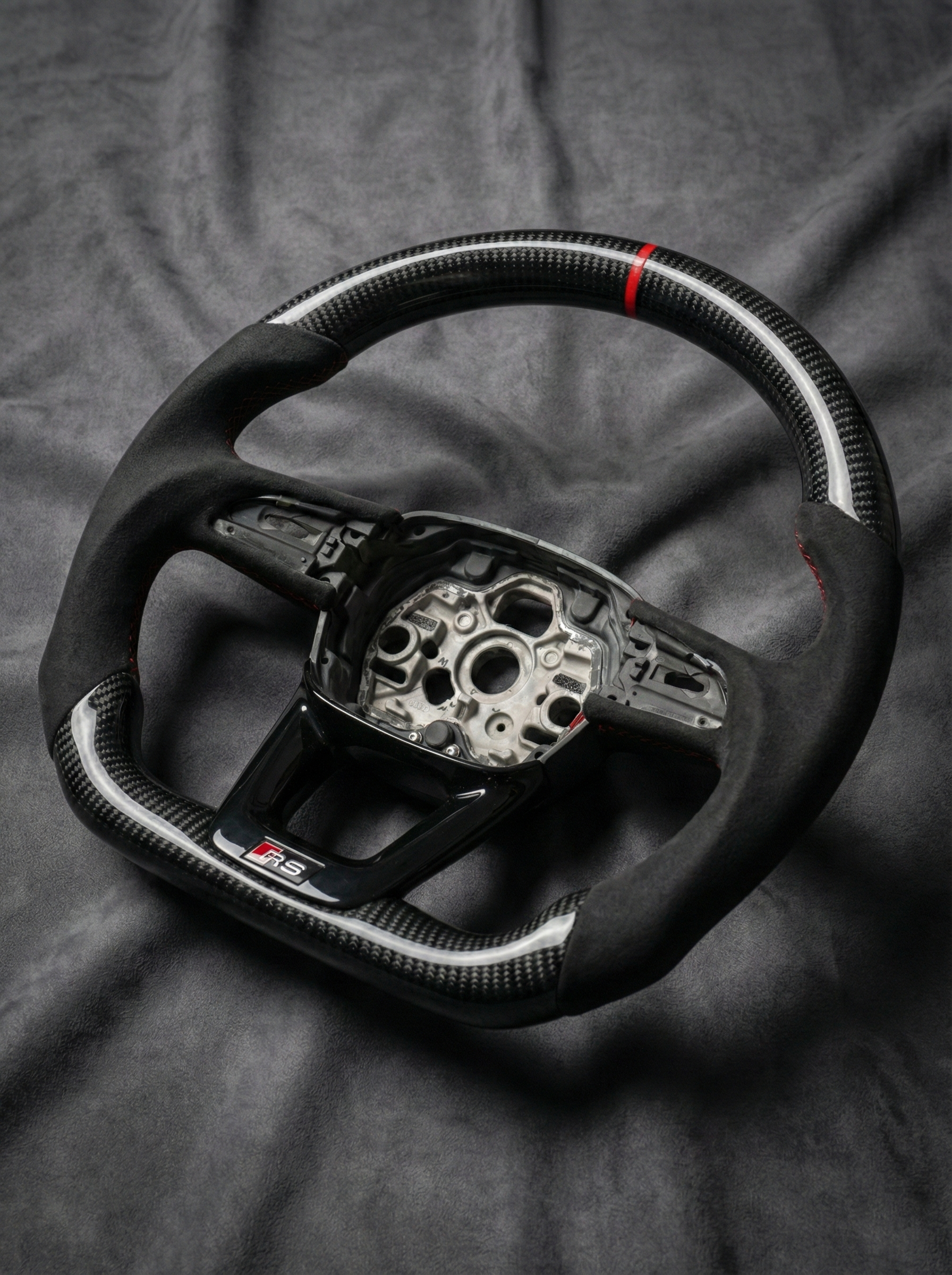 Carbon fiber steering wheel with silver center on a dark fabric background
