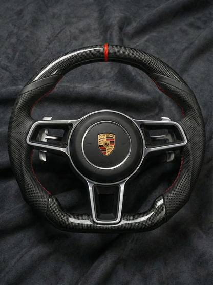 Steering wheel with Porsche logo on a dark fabric background