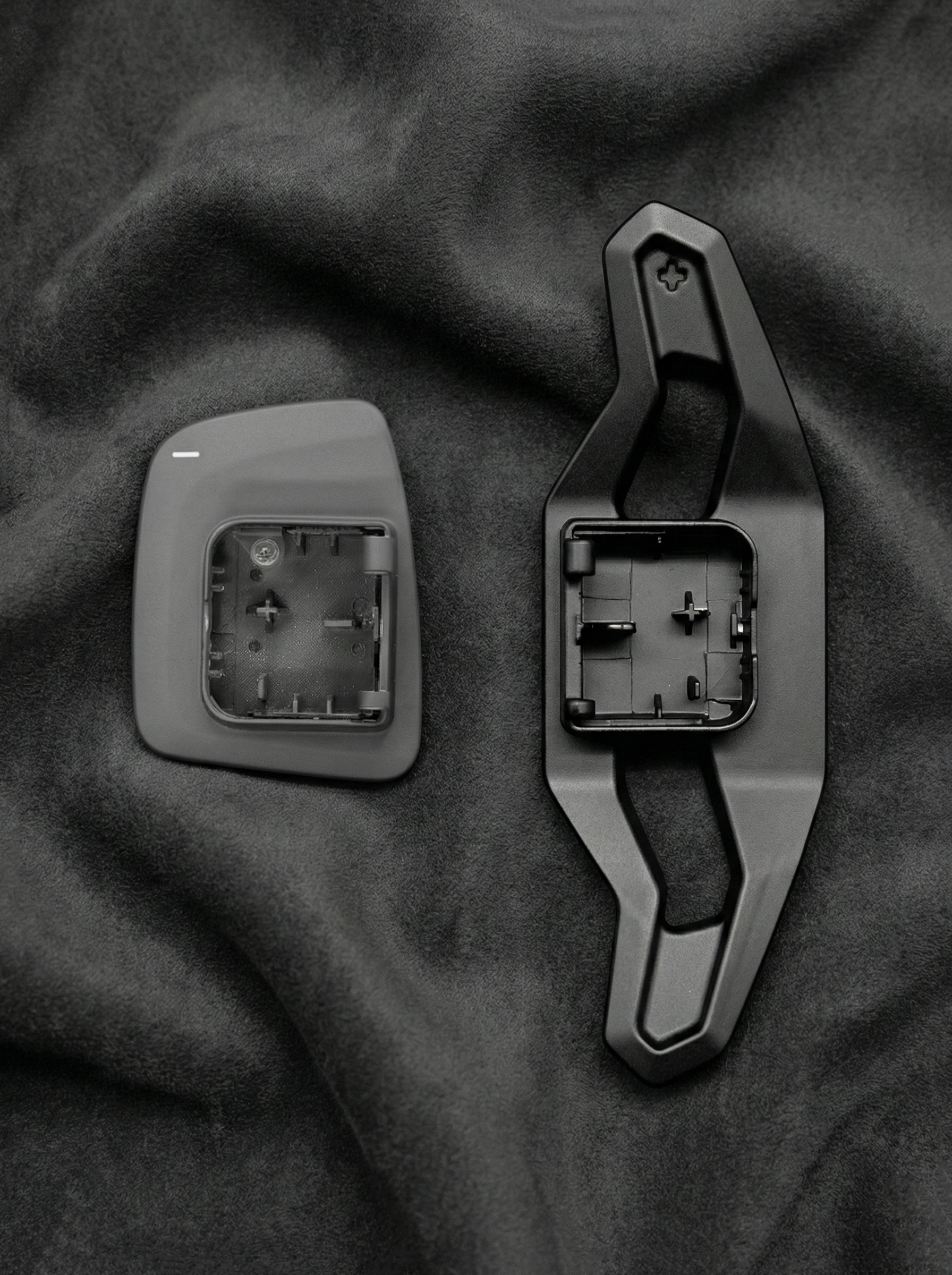 Two car door handles on a dark fabric background