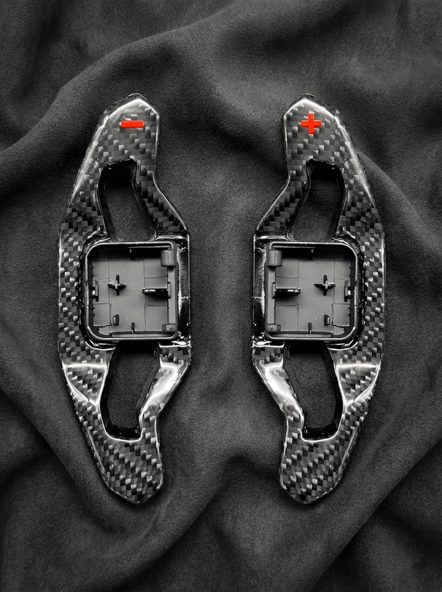 Two carbon fiber components on a dark fabric background