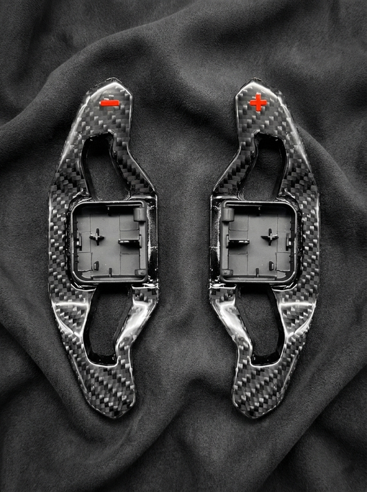 Two carbon fiber components on a dark fabric background